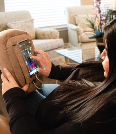 woman brown potato pillow phone older phone stand PhoneSpud phone accessory holds smartphone cell phone while resting in bed gaming watching videos scrolling bedtime phone use helps hand strain carpal tunnel arthritis