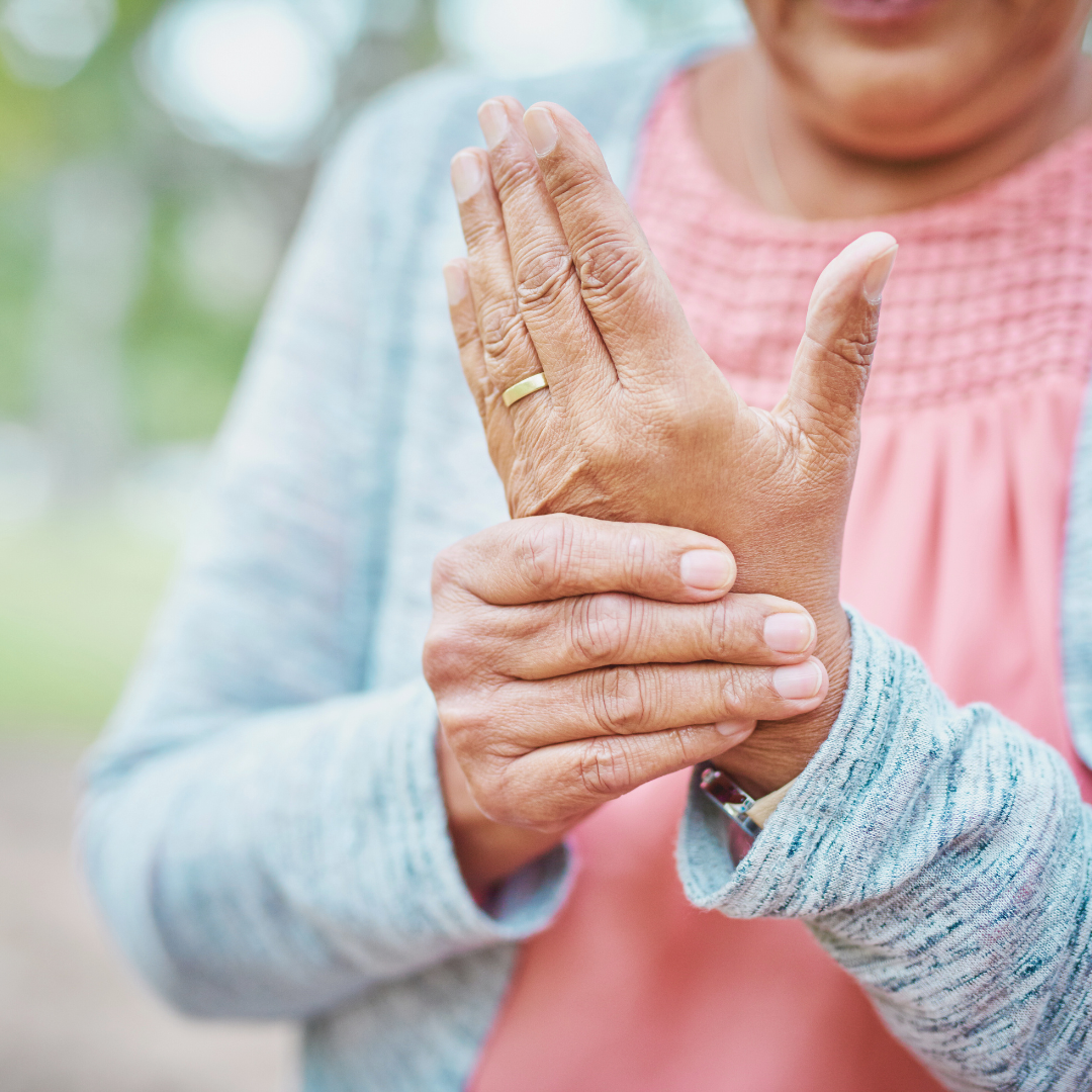 Person holding their wrist with visible arthritis symptoms outdoors
