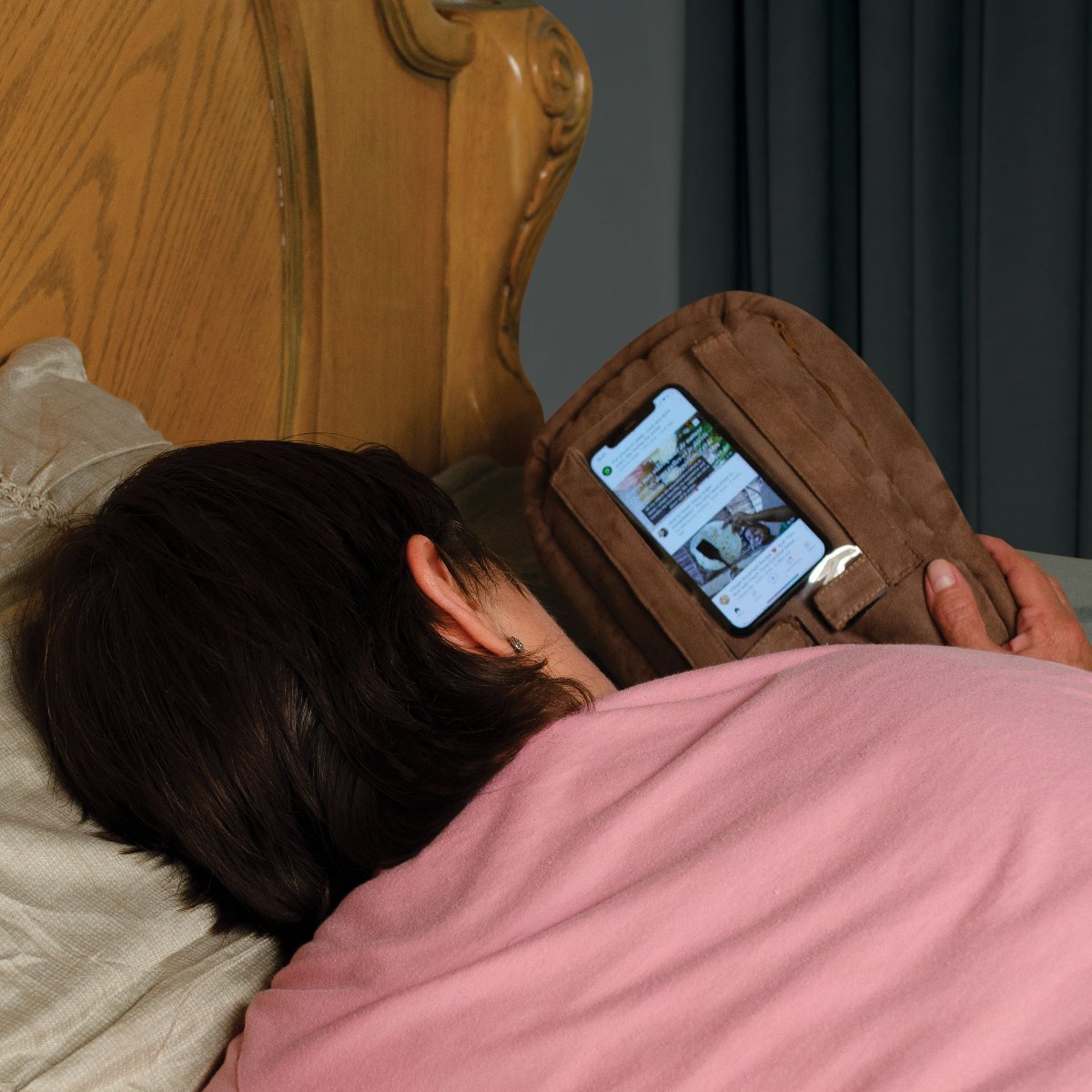 Woman using brown potato pillow phone stand PhoneSpud phone holder phone stand accessory in bed resting recovering watching videos helps hand strain arthritis carpal tunnel