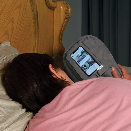 woman resting in bed watching videos on smartphone cell phone in gray pillow phone stand