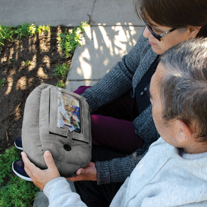a couple in a park setting watching videos using a gray phonespud to hold their phone horizontally